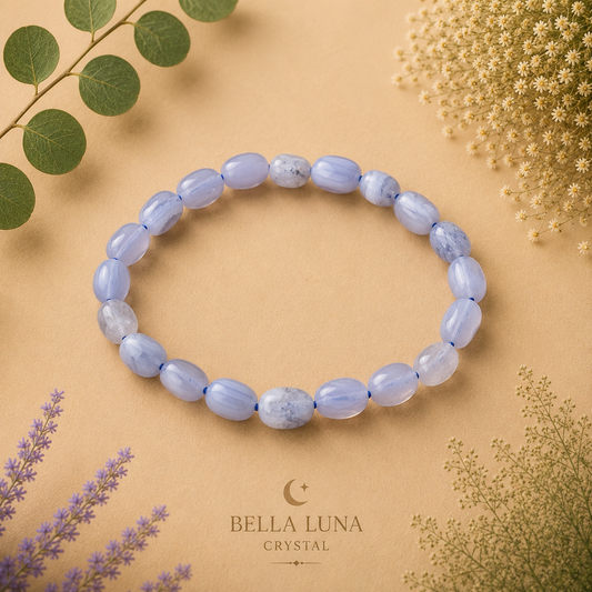 A beaded stretch bracelet made of light blue oval crystals, arranged in a circle on a warm beige background with decorative botanical elements and the Bella Luna Crystal brand logo at the bottom.