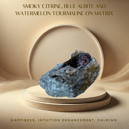 A polished crystal specimen featuring a mix of smoky citrine, blue albite, and watermelon tourmaline, placed on a reflective surface with a warm light background.