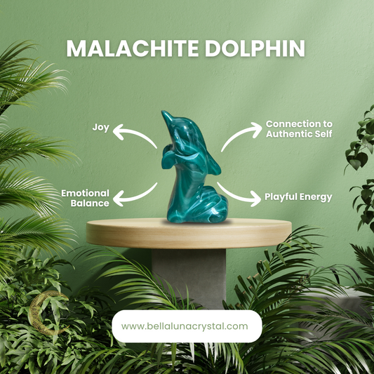 A carved malachite dolphin sculpture on a wooden stand, with greenery in the background, indicating it is part of the Bella Luna Crystal collection.