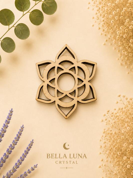 A laser-cut wooden crystal pendant in the shape of a geometric lotus flower, displayed on a warm beige background with decorative dried flowers and green leaves. The brand name 'BELLA LUNA CRYSTAL' is printed at the bottom.