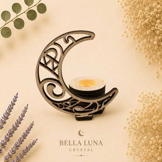 A crescent moon-shaped crystal candle holder with intricate cutout patterns, holding a small tealight candle. The product is styled on a warm beige background with dried flowers and greenery, and the brand name 'BELLA LUNA CRYSTAL' is printed below.