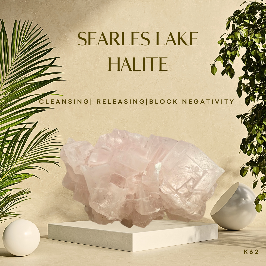 A halite crystal specimen from Searles Lake, CA, displayed on a white stand against a neutral background with palm leaves and a spherical decoration.