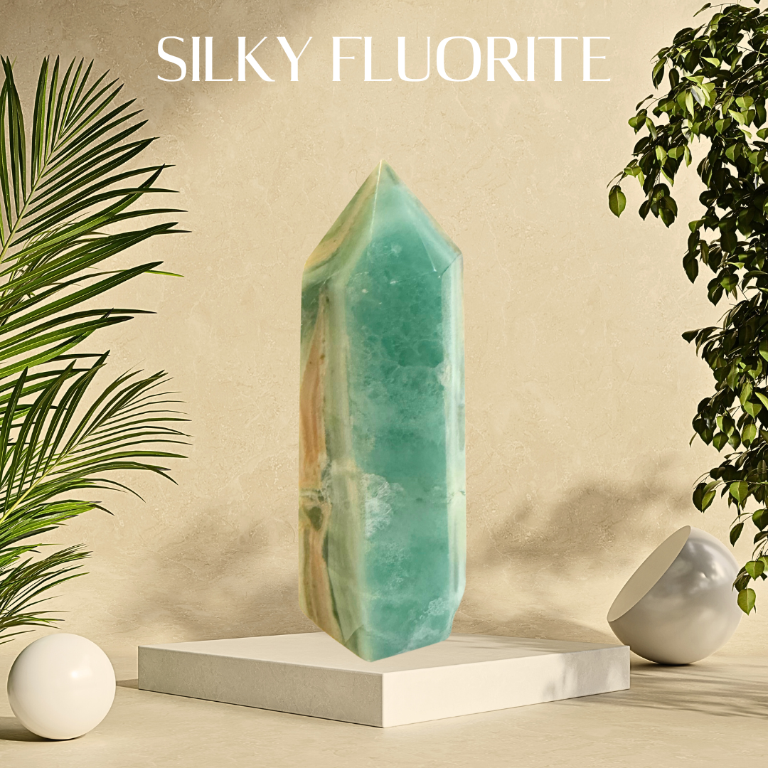 Sleek green fluorite crystal on a white pedestal with plants and a beige background