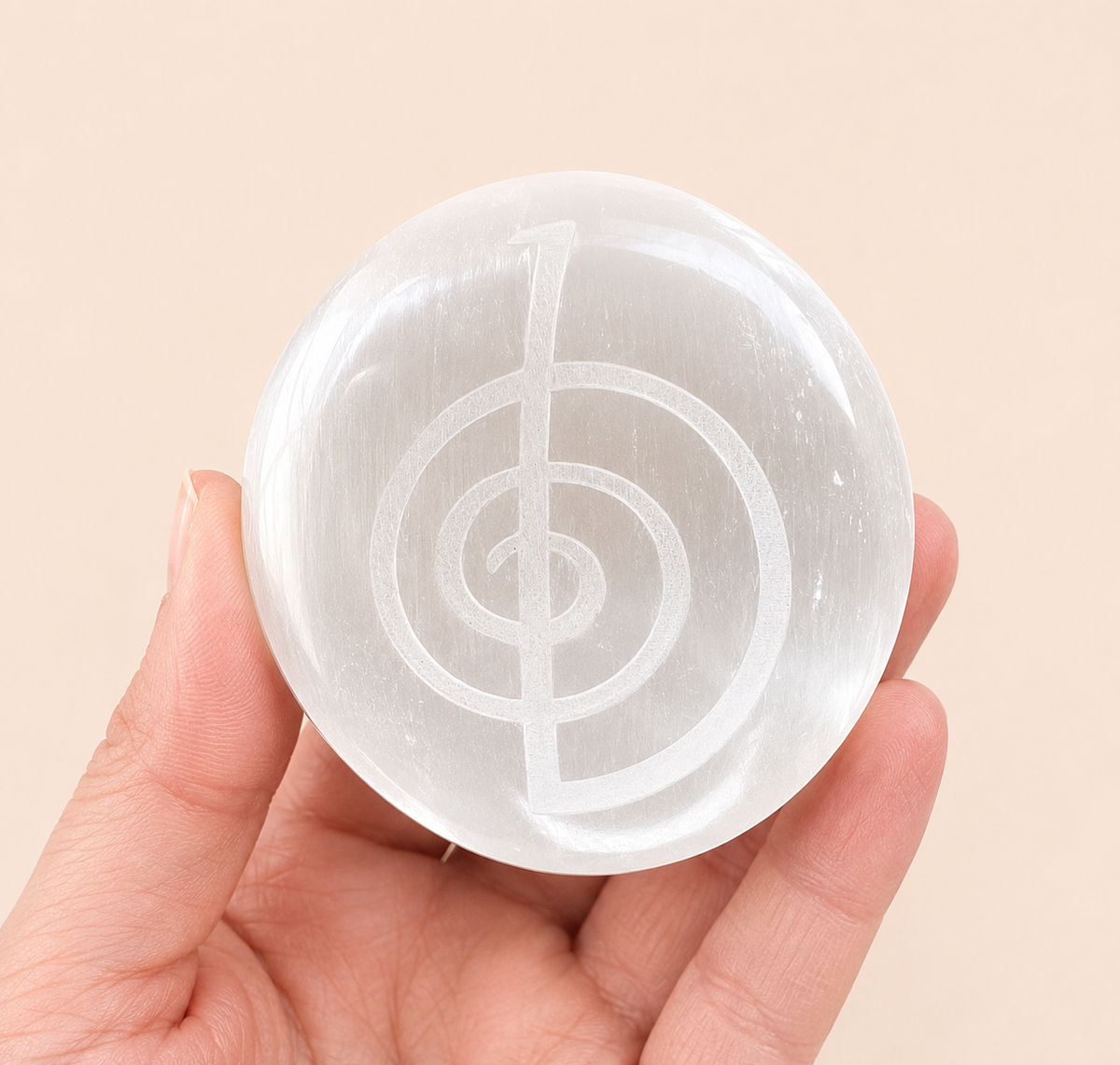 A hand holding a round, translucent white crystal sphere featuring an etched musical treble clef symbol, set against a solid pale beige background.
