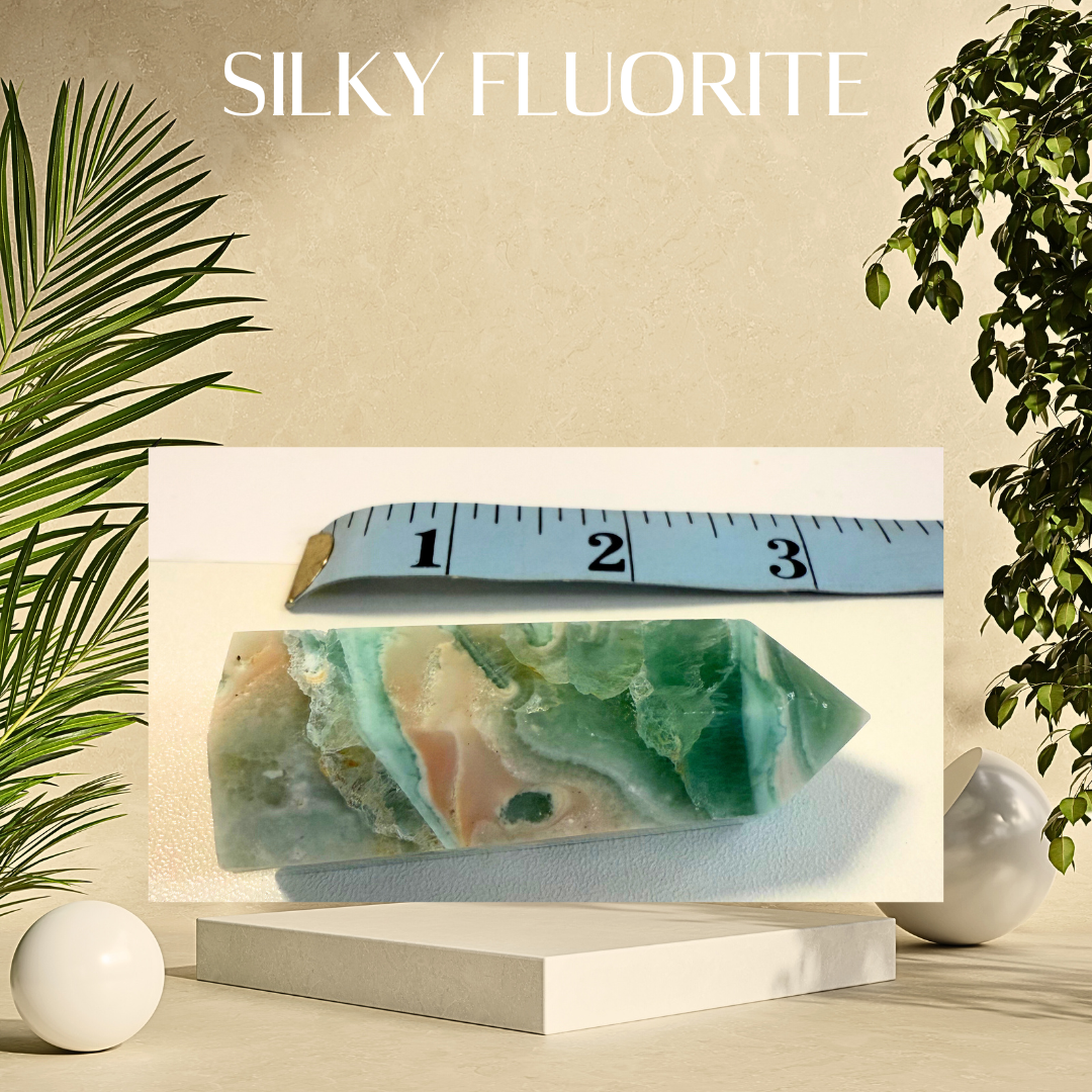 Fluorite crystal on a stand with a ruler for scale, surrounded by plants on a beige background.