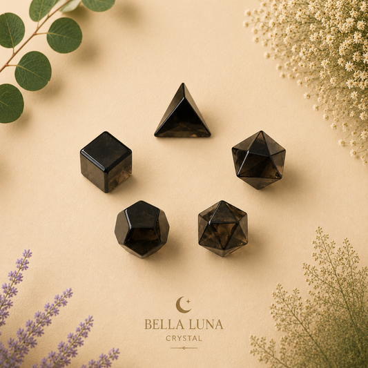 Five polished black smoky crystal geometric shapes arranged on a beige background with decorative botanical elements. The brand name 'BELLA LUNA CRYSTAL' is printed at the bottom center.