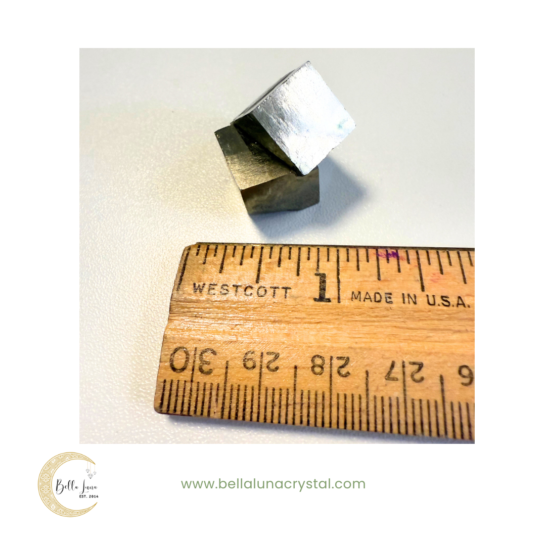 Metal cube next to a wooden ruler on a white background with 'Bella Luna Crystal' branding.
